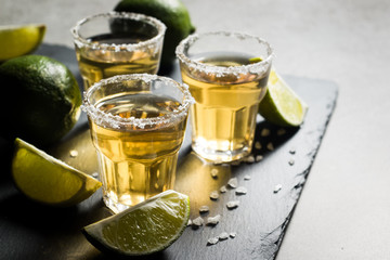 Macro photo of shots of gold Mexican tequila with lime and salt on wooden rustic background. Alcoholic drink concept. selective focus.