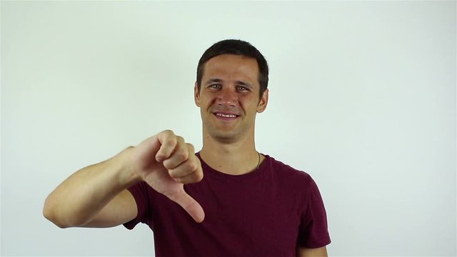 Handsome young man shows his thumb down and shaking his head negatively while talking on video chat.Portrait on a white background.