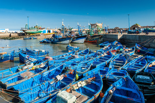 A Fleet Of Blue Fishing Boats Huddled Together In The Port Of Essaouira In Morocco.