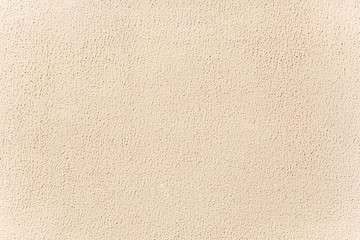 Beige stucco background. Bright wall lit by sunshine