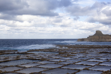 Salt pans and rough sea on Gozo, Malta.