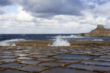 Salt pans and rough sea on Gozo, Malta.