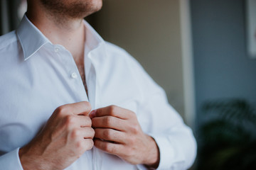 Grooms morning preparation, handsome groom getting dressed and preparing for the wedding, in dark...