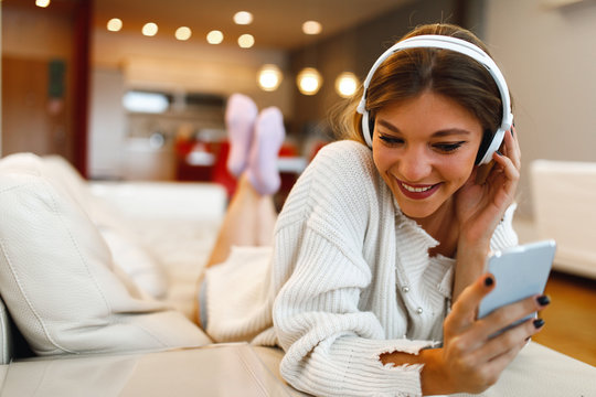 Young woman listening to music with headphones and smartphone on the sofa