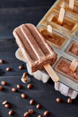 Sweet homemade coffee ice lolly on a dark wooden table with coffee beans. Top view