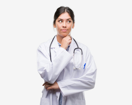 Young hispanic doctor woman serious face thinking about question, very confused idea