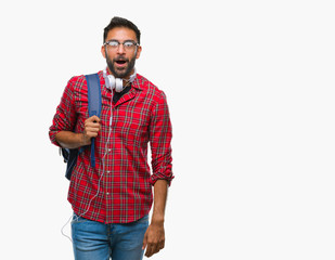 Adult hispanic student man wearing headphones and backpack over isolated background afraid and shocked with surprise expression, fear and excited face.