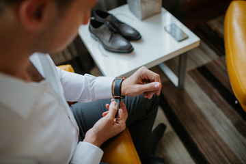 Grooms morning preparation, handsome groom getting dressed and preparing for the wedding, in dark blue suit.