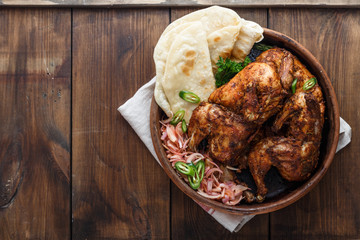 Tandoori chicken. Half of tandoori chicken served with lime slices and cilantro. Top view, blank space