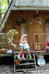 Two sisters embrace on the porch of a house in the village