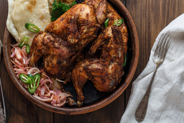 Tandoori chicken. Half of tandoori chicken served with lime slices and cilantro. Top view, blank space