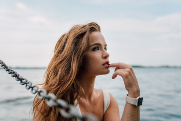 Woman wearing smartwatch looking into distance in front of lake - 219862709