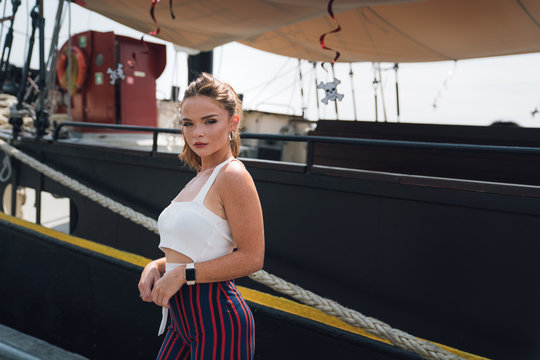 Fashionable woman standing in front of docked boat