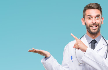 Young handsome doctor man over isolated background amazed and smiling to the camera while presenting with hand and pointing with finger.