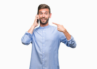Young handsome man speaking on the phone over isolated background very happy pointing with hand and finger