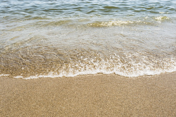 sea shoreline with waves, sandy beach on a clear sunny day, close-up nature abstract background