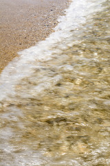 sea shoreline with waves, sandy beach on a clear sunny day, blurred nature abstract background