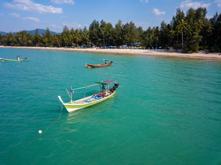Fototapeta na wymiar Aerial drone view of colorful traditional Longtail boats at anchor off a sandy beach in Thailand