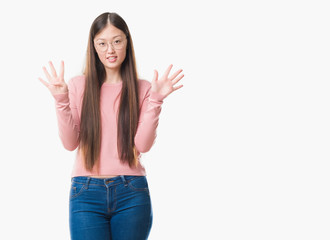 Young Chinese woman over isolated background wearing glasses showing and pointing up with fingers number nine while smiling confident and happy.