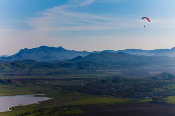 Fototapeta na wymiar Experienced hang-glider hovering above hilly landscape