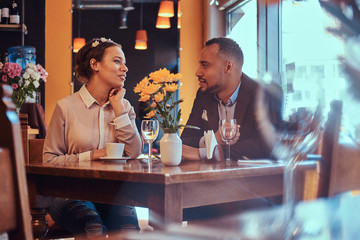 Happy attractive African-American couple in love having a great time together in a restaurant at their dating. A beautiful couple enjoying each other.