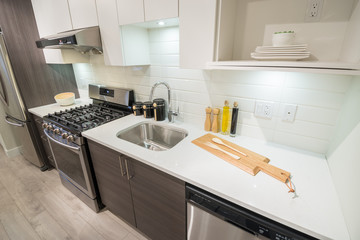 Modern, bright, clean kitchen interior with stainless steel appliances in a luxury apartment.