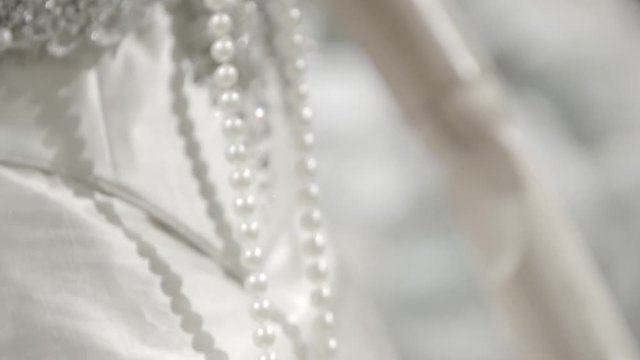 A white lacy dress on a female mannequin. Dettail of a wedding gown with necklace made of pearls. Fashion concept.