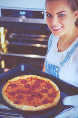 Happy young woman cooking pizza at home