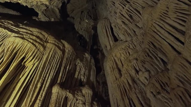 Astonishing interior of dimly lit cave or cavern with stalactites hanging from ceiling and stalagmites rising from floor. Gorgeous view of impressive speleothems or mineral rock formations. 
