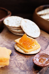 Water cracker, cheddar cheese and homemade Salted Vanilla Cantaloupe jam. Extreme shallow depth of field with selective focus on appetizer in center.
