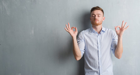 Young redhead business man over grey grunge wall relax and smiling with eyes closed doing meditation gesture with fingers. Yoga concept.