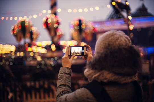 Woman Taking Pictures of European Christmas Market Scene on Smartphone