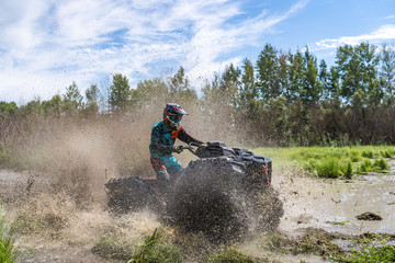 ATV Quad rides fast on big dirt and makes splashes of dirty water