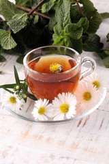 cup of tea with chamomile flowers on rustic background