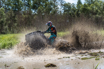 ATV Quad rides fast on big dirt and makes splashes of dirty water