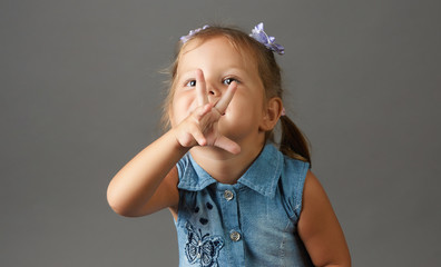 Portrait of Happy 3 year old little girl showing three fingers on gray background with copy space