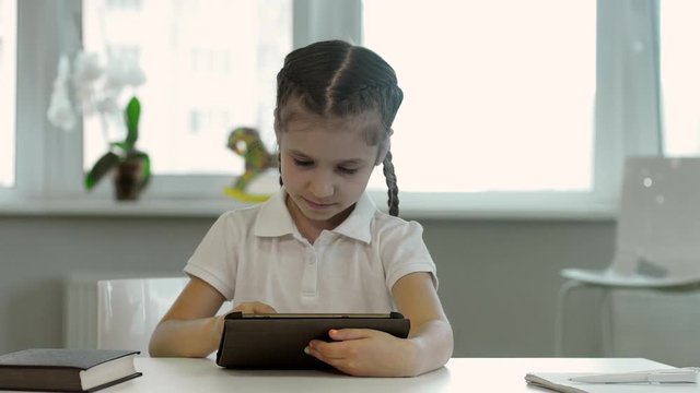 A little girl with pigtails can not find the right information on the tablet and spreads information because of this