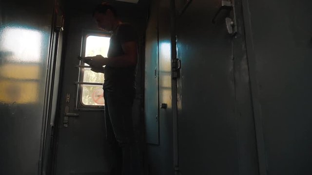 the man silhouette is standing on the train Railway carriage holding a smartphone and . slow motion video. man writes messages in the smartphone in the train social media. man with smartphones train