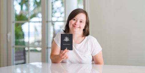 Fototapeta na wymiar Down syndrome woman at home holding australian passport with a happy face standing and smiling with a confident smile showing teeth