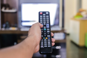 The man changes the channels on the remote control of the TV.