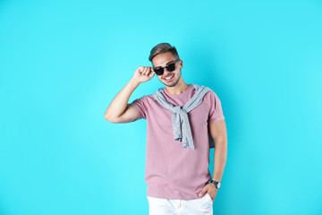 Young man with trendy hairstyle on color background