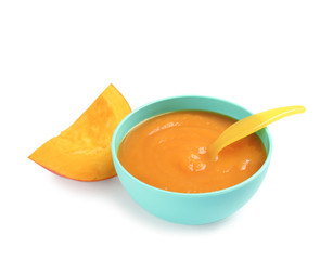 Bowl of healthy baby food and pumpkin slice on white background