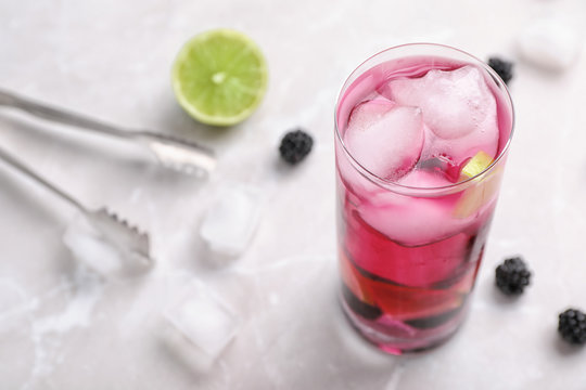 Glass with iced blackberry lemonade on table
