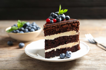 Plate with slice of chocolate sponge berry cake on wooden table