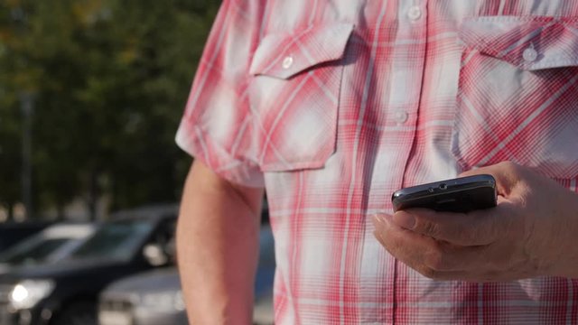 A Man In A Plaid Shirt With the Mobile Phone In Hand