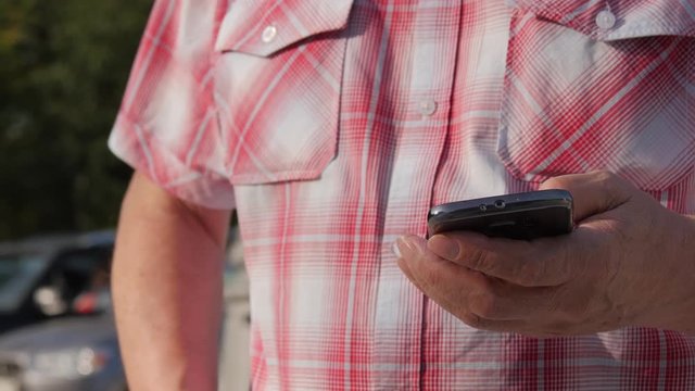A Man In A Plaid Shirt With the Mobile Phone In Hand