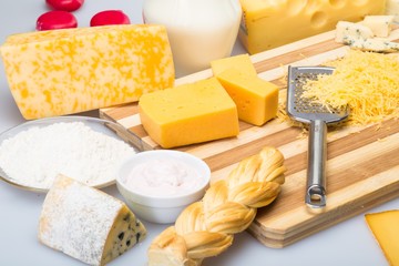 Cheeses and Milk on the Wooden Platter - on the Grey Background