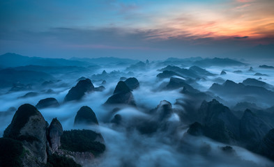 Fototapeta na wymiar Bajiaozhai National Forest Park in Ziyuan County, Guangxi Province China. Dawn, The Sea of Clouds, Fog and Mist floating between the Danxia Landforms, Appearing Like Whales Swimming in an Ocean