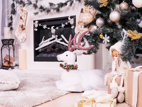 Christmas deer under New Year Tree with gifts, presents. Christmas stocking over fireplace decor, New Year's card scenery. Snowmans with stars and candels. New Year concept.