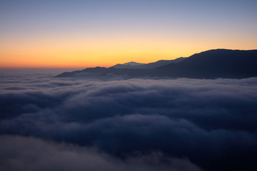 Yuanyang County - Yunnan Province, China. Dawn, Sunrise panoramic view, sea of clouds with an orange glow behind a mountain silhouette. Above the clouds, silhouette, mountain background, red horizon